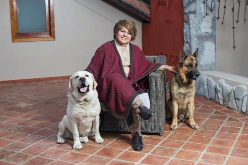 a woman sitting in a chair with two dogs at Intiterra Apart Hotel Villas in Urubamba