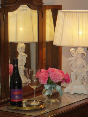 a bottle of wine on a table with a lamp and flowers at Casa Panvinio in Verona