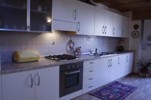 a kitchen with white cabinets and a stove and a sink at Appartamento Al Castello in Levico Terme