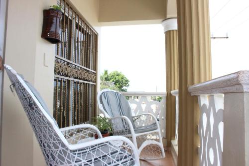 twee witte stoelen op een balkon met een raam bij Elisa Furnished Apartments (Puerto Plata City) in San Felipe de Puerto Plata