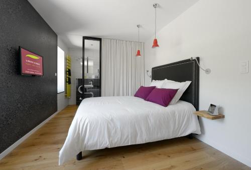 a bedroom with a large white bed with purple pillows at La Bonne Auberge in Clerval