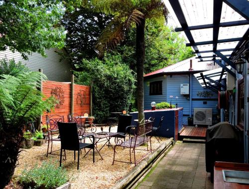 a patio with chairs and a table and a house at KUBBA ROONGA GUESTHOUSE - Boutique Luxury Spa Retreat & Gardens - Blue Mountains in Blackheath