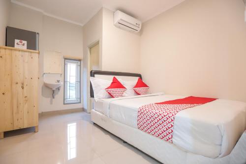 a bedroom with a large white bed with red pillows at OYO 387 Alfa Guest House in Jakarta