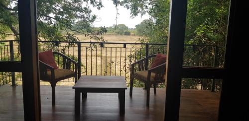 a porch with two chairs and a table and a fence at Wilpattu Tree House in Wilpattu