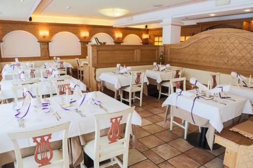 a dining room with white tables and chairs at Dolce Avita Hotel Spa & Resort in Andalo