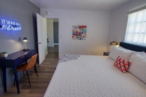 a bedroom with a white bed and a desk and a desk at 23 Palms Suites - Midtown Wynwood in Miami