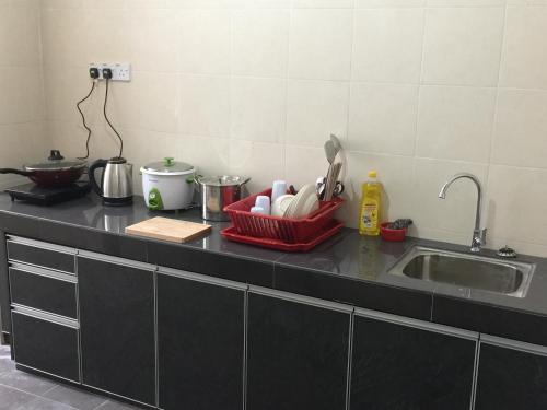 a kitchen counter with a sink and a red basket with utensils at Cameron Cactus Apartment @ Pangsapuri Kaktus in Brinchang