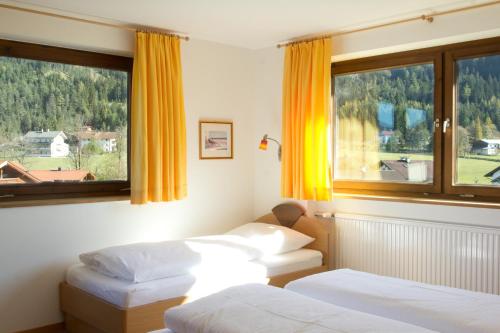 two beds in a room with two windows at Haus Karoline in Achenkirch