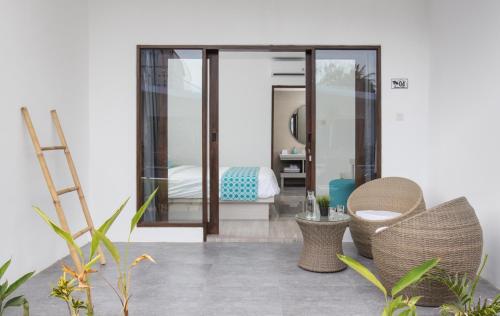 a patio with two chairs and a bed in a room at Jago Gili Air in Gili Islands