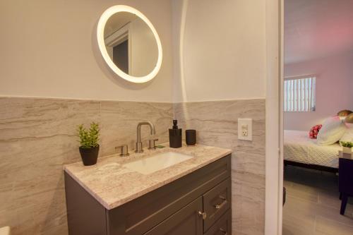 a bathroom with a sink and a mirror and a bed at 23 Palms Suites - Midtown Wynwood in Miami