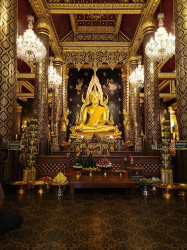 a temple with a large gold statue in a room at Kraisaeng Place in Phitsanulok