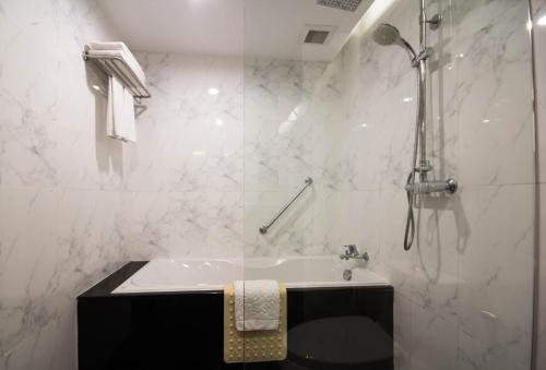 a white bathroom with a shower and a sink at Sima Thani Hotel in Nakhon Ratchasima