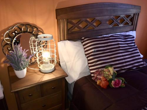a bed with a wooden headboard and a night stand with a lamp at Apartamento La Alcancía in Toledo