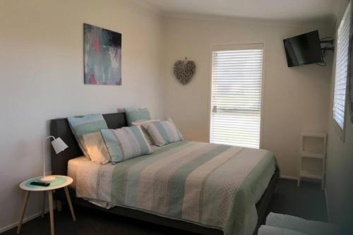 um quarto com uma cama, uma mesa e uma televisão em The Lake Guesthouse em Budgewoi