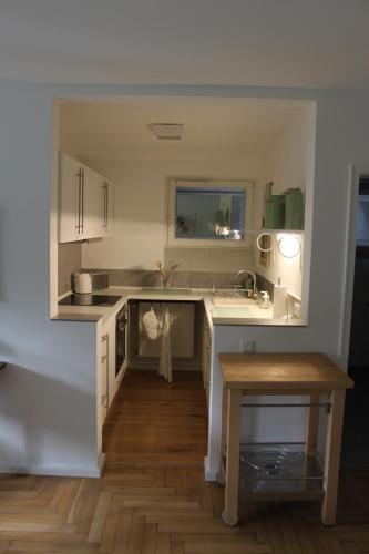 a kitchen with white cabinets and a wooden floor at Schönes Appartement mit Gartenblick in Baden-Baden