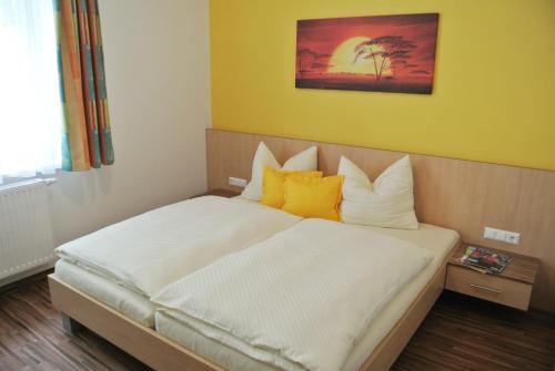 a bedroom with a large bed with yellow walls at Frühstückspension Paradiesgartl in Amstetten