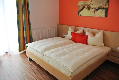a bedroom with a bed with two red pillows at Frühstückspension Paradiesgartl in Amstetten