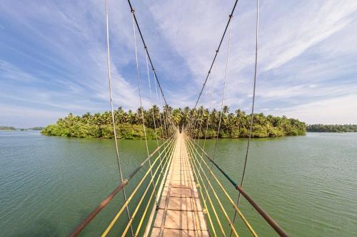 a suspension bridge over a body of water at SaffronStays Suvarna Sangam, Udupi in Udupi