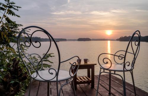two chairs and a table in front of a body of water at SaffronStays Suvarna Sangam, Udupi in Udupi