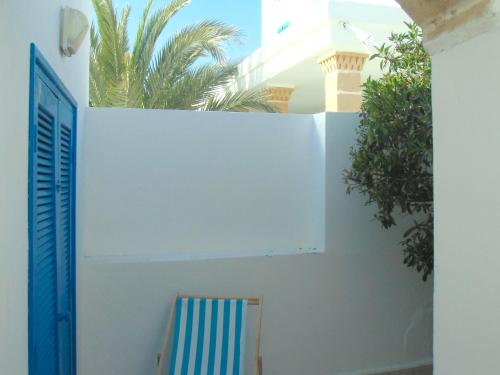 a white wall with a blue door and a chair at Hotel Villa Soleil in Sidi Kaouki