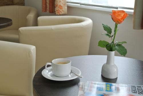 a cup of coffee and a vase with a flower on a table at Frühstückspension Paradiesgartl in Amstetten