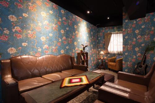 a living room with a leather couch and floral wallpaper at Cho Hotel in Taipei