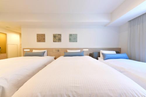 two beds in a room with white at Vessel Inn Sakae Station in Nagoya