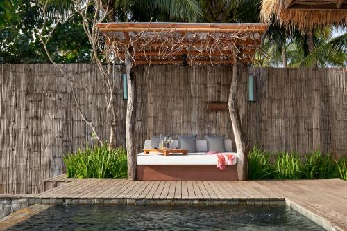 a resort bed with blue pillows next to a swimming pool at Song Saa Private Island in Song Saa Private Island