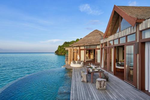 a house on the water with a wooden deck at Song Saa Private Island in Song Saa Private Island