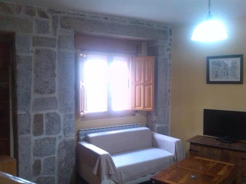 sala de estar con sofá blanco y ventana en La plaza, en Villatoro