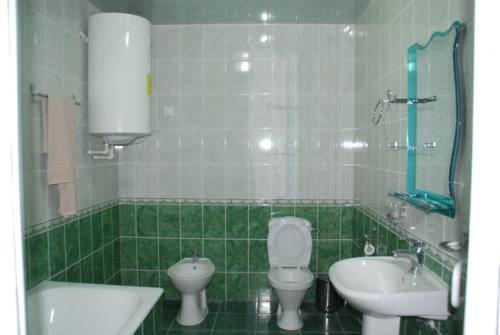 W wyłożonej zielonymi kafelkami łazience znajduje się toaleta i umywalka. w obiekcie Toshkent Hotel w Andiżanie