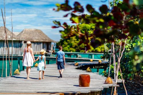 a family walking on a wooden bridge over the water at Song Saa Private Island in Song Saa Private Island