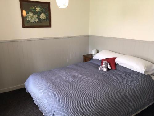 un osito de peluche sentado en una cama en un dormitorio en Granny Stringer’s Cottage en Roxburgh