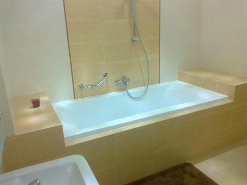 a bathroom with a tub with a shower and a sink at Penzion Iris in Rajecké Teplice