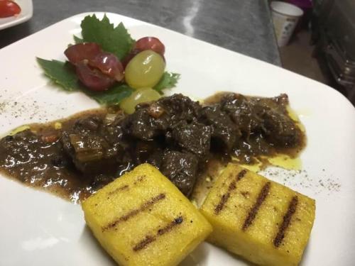 a white plate of food with meat and vegetables at Bio Agriturismo Il Melograno di Banditella Ristorante in Alberese