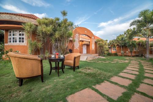 a patio with chairs and a table in a yard at Vijayshree Resort, Hampi in Hampi
