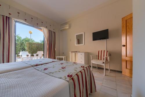 a bedroom with a bed and a large window at Hotel Torre De Los Guzmanes in La Algaba
