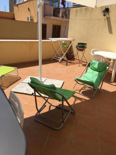 a patio with chairs and tables and an umbrella at La casa di nonna Rosa in Isola delle Femmine
