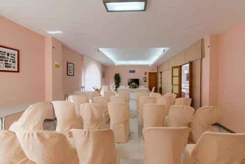 a room with white chairs and a table in it at Hotel Torre De Los Guzmanes in La Algaba