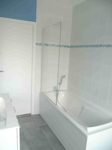 une salle de bain blanche avec une baignoire et une douche dans l'établissement Villa centre ville à 100m de la plage, pour 20 personnes, à Grandcamp-Maisy