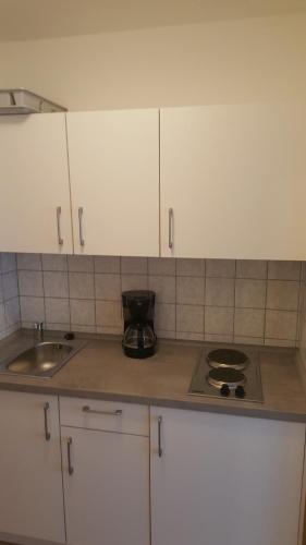 a kitchen with white cabinets and a stove top oven at Appartementhaus Wimmerhof in Bad Füssing