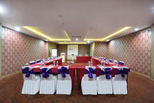 a banquet hall with red and white tables and purple bows at Quest San Denpasar by ASTON in Denpasar