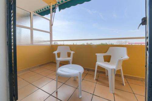 two white chairs and a stool on a balcony at Hotel Torre De Los Guzmanes in La Algaba