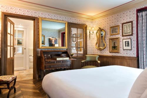a bedroom with a bed and a desk and a mirror at Airelles Gordes, La Bastide in Gordes