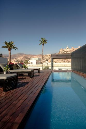 a swimming pool with a wooden deck and palm trees at Aire Hotel & Ancient Baths in Almería