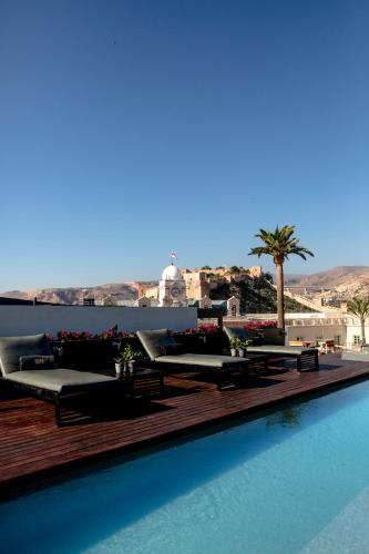 a swimming pool with chaise lounges on top of a resort at Aire Hotel & Ancient Baths in Almería