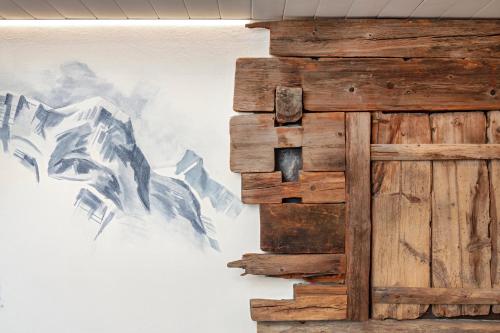 a painting on a wall next to a wooden door at Hotel Antika in Zermatt