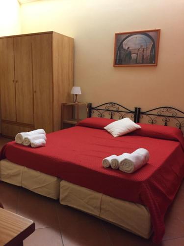 a bedroom with a large red bed with towels on it at La casa di nonna Rosa in Isola delle Femmine