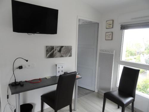 Cette chambre comprend un bureau avec deux chaises et une télévision murale. dans l'établissement Au Cadran Solaire, à Nantes