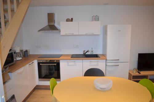 a kitchen with a yellow table with chairs and a sink at Logement Vendée in Saligny